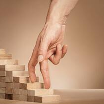 Eine Hand fährt über eine kleine Holztreppe