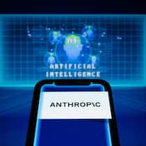 Das Anthropic-Logo wird auf einem Smartphone vor dem Hintergrund einer visuellen Darstellung künstlicher Intelligenz angezeigt.