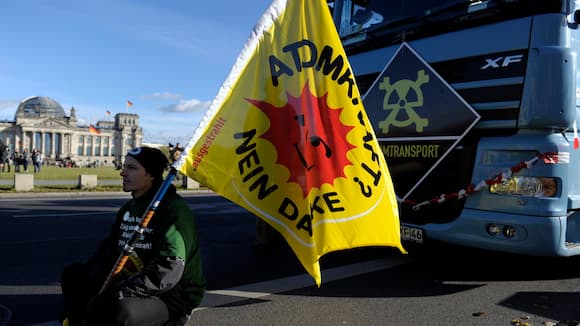Ein Aktivist sitzt am Montag (25.10.10) in Berlin bei einer Demonstration gegen Atomkraft mit einer Flagge vor dem Reichstag. In Berlin haben am Montag mehrere Hundert Menschen mit einem nachgebauten Castor-Transporter gegen Atomkraft demonstriert. Rund 300 Demonstranten zogen nach Veranstalterangaben von der Zentrale des Energiekonzerns Vattenfall in Richtung Bundestag. Die Organisation Campact organisierte einen symbolischen Castor-Transport vom Atomendlager Gorleben nach Berlin.