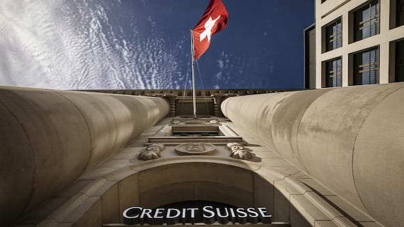 The logo of Swiss bank Credit Suisse is seen beside a Swiss flag on a building in Lucerne, Switzerland, on March 16, 2023. Credit Suisse, which was beset by problems long before the U.S. bank failures, said Thursday that it would exercise an option to borrow up to 50 billion francs ($53.7 billion) from the Swiss National Bank. (KEYSTONE/Michael Buholzer)