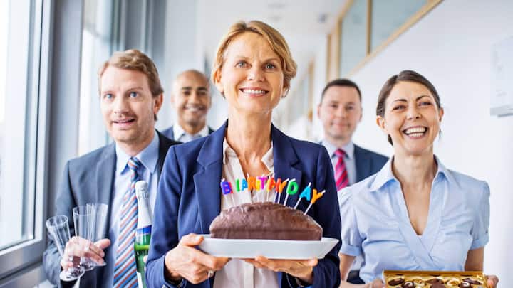 Happy group of business people celebrating birthday in office
