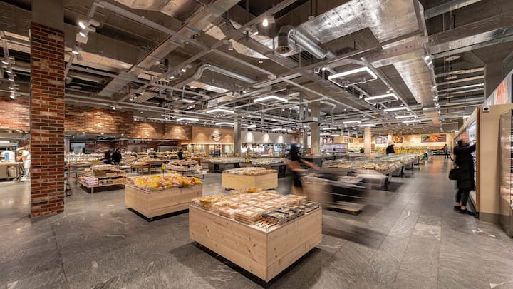 Coop vs. Migros: Supermärkte: Coop hat den Umbau aller Filialen von ­langer Hand geplant. Mehr Holz soll für Marktplatzstimmung sorgen, und in grossen Supermärkten stellt das Personal viele Produkte frisch her. Die Migros tüftelt noch an einem neuen einheitlichen Ladenkonzept und ist im Vergleich um Jahre im Rückstand.