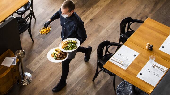 A waiter of "La Brasserie de Montbenon" restaurant brings dishes food to customers during the spread of the pandemic Coronavirus (COVID-19) disease in Lausanne, Switzerland, Monday, May 11, 2020. In Switzerland from today, the Swiss authorities lifted second part of the lockdown. (KEYSTONE/Jean-Christophe Bott)