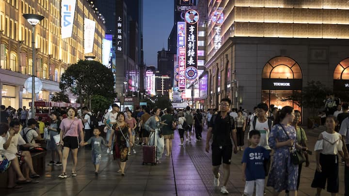 Pedestrians walk through the Nanjing Road shopping district at night in Shanghai, China, on Monday, July 29, 2019. Chinese trade negotiators will host their U.S. counterparts at a landmark of jazz-era Shanghai on the city's riverside Bund, re-opening trade talks with a marked change of atmosphere after an almost three-month hiatus. Photographer: Qilai Shen/Bloomberg