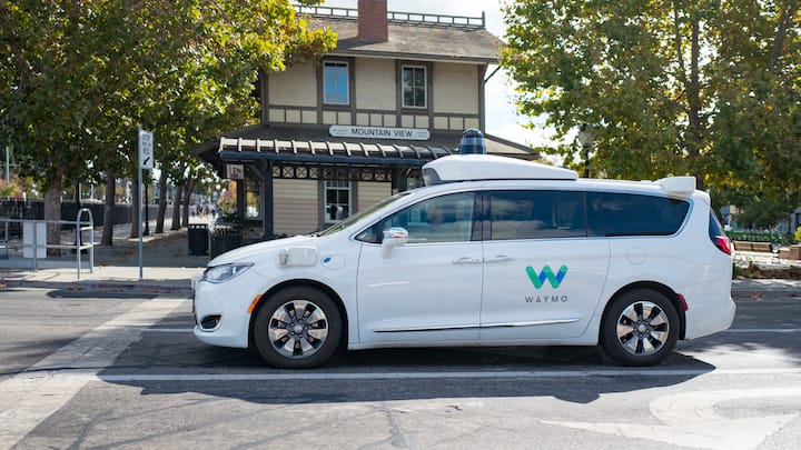 Close-up of self driving minivan, with LIDAR and other sensor units and logo visible, part of Google parent company Alphabet Inc, driving past historic railroad station with sign reading Mountain View, in the Silicon Valley town of Mountain View, California, with safety driver visible, October 28, 2018. (Photo by Smith Collection/Gado/Getty Images)