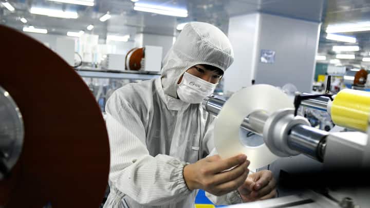 DONGGUAN, CHINA - MAY 20: Employees wearing protective suits work on the production line of optical film products at a workshop of Guangzhi Photoelectric Co., Ltd on May 20, 2020 in Dongguan, Guangdong Province of China. (Photo by Zhan Youbing/VCG via Getty Images)