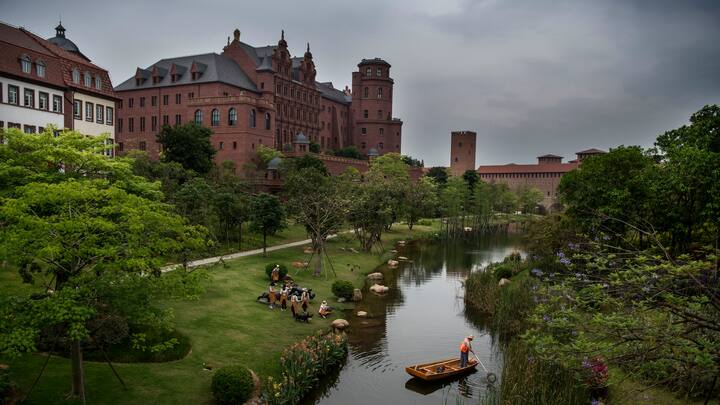 A worker cleans a waterway as office buildings are seen at Huawei's new sprawling 'Ox Horn' Research and Development campus on April 12, 2019 in Dongguan, near Shenzhen, China.