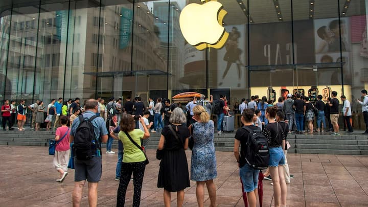 In this Friday, Sept. 21, 2018, photo, foreign tourists watch people queue in line to enter the Apple Store for the debut of the latest iPhones in Shanghai. China imposed new tariff hikes on U.S. goods on Monday, Sept. 24, 2018, and accused Washington of bullying, giving no sign of compromise in an intensifying battle over technology that is weighing on global economic growth. (Chinatopix via AP) (KEYSTONE/AP CHINATOPIX/)