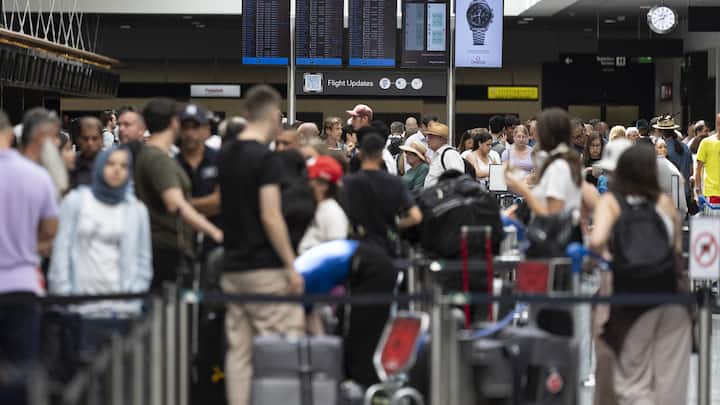 Passengers look at screens informing them of the flight situation, on Friday, 19 July 2024, at the airport Zurich in Kloten, Switzerland. Due to a worldwide IT breakdown, check-in for air travellers and flight operations are severely restricted and most flights are delayed or cancelled. Swiss air traffic control Skyguide is also affected by the IT disruption and has reduced the capacity of Swiss transit traffic as an immediate precautionary measure. (KEYSTONE/Gaetan Bally)