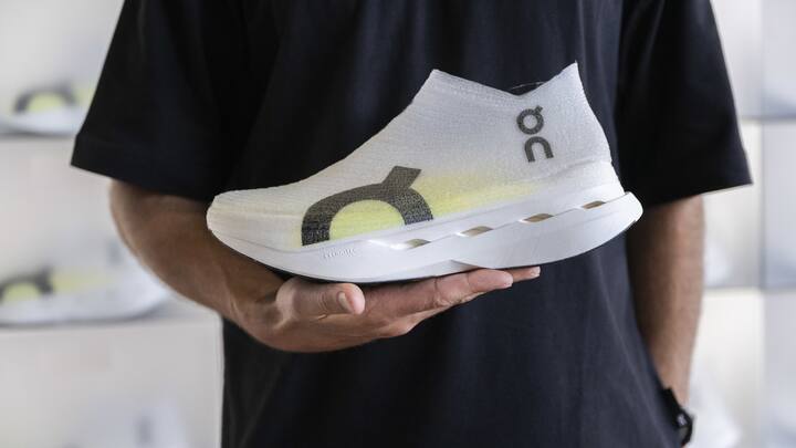 Ein Mann praesentiert einen bespruehten Sportschuh von On, dieser wird mit einem Tintenstrahldrucker bedruckt und anschliessend mit ultravioletten Strahlen fixiert, aufgenommen anlaesslich der Eroeffnung des LightSpray Produktionsstandortes von On, eine vollautomatisierte Schuhproduktion, am Mittwoch, 2. Juli 2025, Zuerich. (KEYSTONE/Ennio Leanza)
