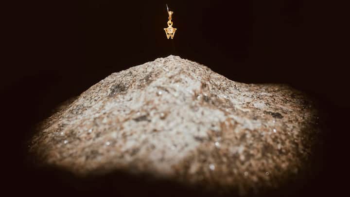 Das Logo der Goldschmiede Wellendorff, ein Brillant-W, wird auf einem Stein inszeniert.
