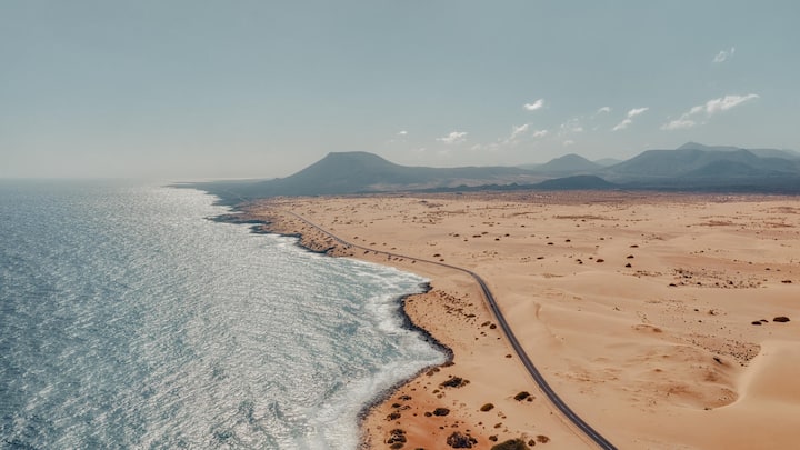 Rocky coastline and highway with golden sand and blue water