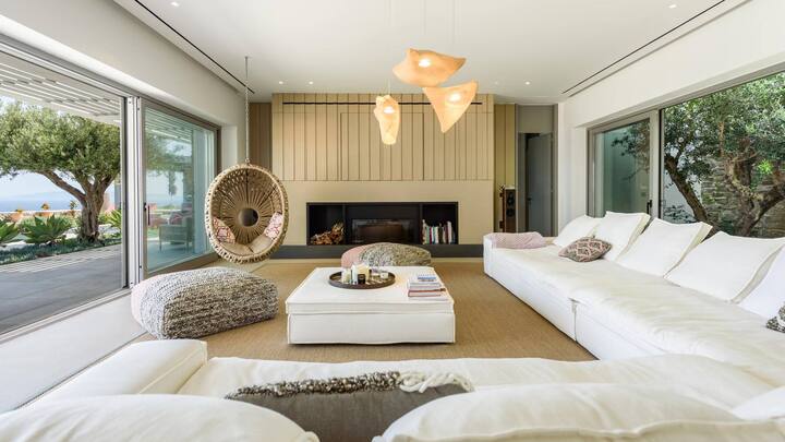 Die Sofalandschaft im Wohnzimmer ist von Fabbrica aus Athen. Den Hängesessel, die Poufs und die kuscheligen Kissen fand man bei lokalen Händlern in Paros.