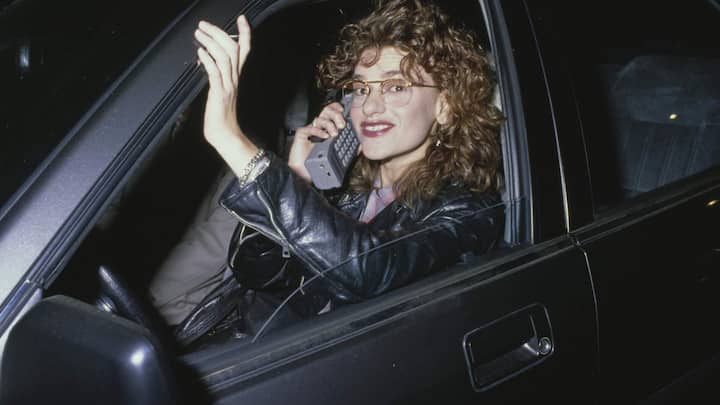 Mobiltelefonie, 1980Das Telefon gab es schon lange, auch das Mobilfunknetz gab es bereits seit 1958. Aber ab 1978 kam mit dem zellulären Mobilfunknetzneuer Schwung in die Mobiltelefonie. Bis aber jede und jeder wie Schauspielerin Sandra Bernhard ortsunabhängig und selbst am Lenkrad telefonieren konnte, sollten noch zwanzig Jahre vergehen. Handys brachten ­Veränderungen in der Arbeitsorganisation und im Management mit sich. Die Debatte um die «Work-Life-Balance» begann.