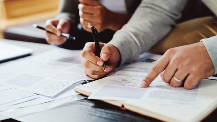 Closeup shot of an unrecognizable couple going through paperwork together at home