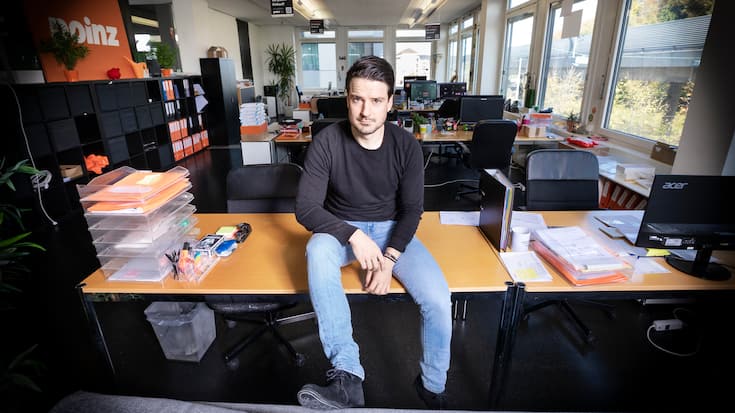 Startup Poinz, Robert Blum sitzt auf einem Tisch in seinem Büro.