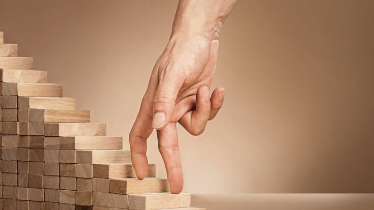 Eine Hand fährt über eine kleine Holztreppe