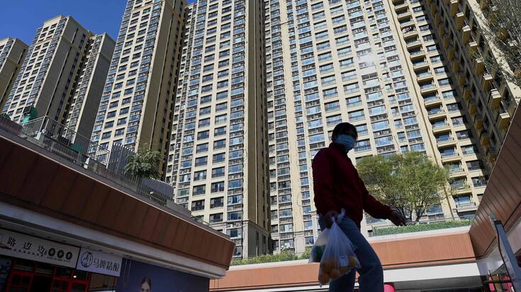 A woman walks in front of a housing complex by Chinese property developer Evergrande in Beijing