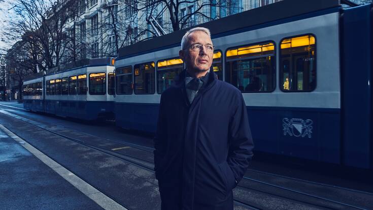 Axel Lehmann, Präsident der Credit Suisse, steht vor einem Zürcher Tram und schaut auf die Seite.