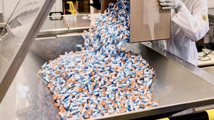 An employee of the medical technology company Ypsomed fills assembled safety pen needles into a packaging machine, pictured at the Ypsomed production site in Burgdorf, Canton of Berne, Switzerland, on August 10, 2018. Ypsomed develops and manufactures injection systems for self-medication. (KEYSTONE/Christian Beutler)