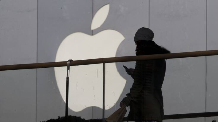 A woman using a phone walks past Apple's logo near its retail outlet in Beijing Monday, Dec. 23, 2013. Apple and China Mobile announced a long-anticipated agreement Monday to bring the iPhone to the world's biggest phone company. The iPhone, once hugely popular in China, has been eclipsed by the rise of lower-priced rival smartphones from Samsung and Chinese companies. (AP Photo/Ng Han Guan)