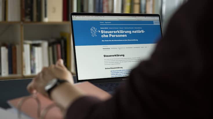 Eine Frau konsultiert an einem Laptopbildschirm Informationen betreffend der Steuererklaerung Kanton Zuerich