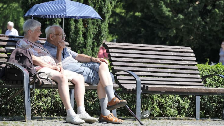 Ein älteres Paar sitzt auf einer Bank im Park.