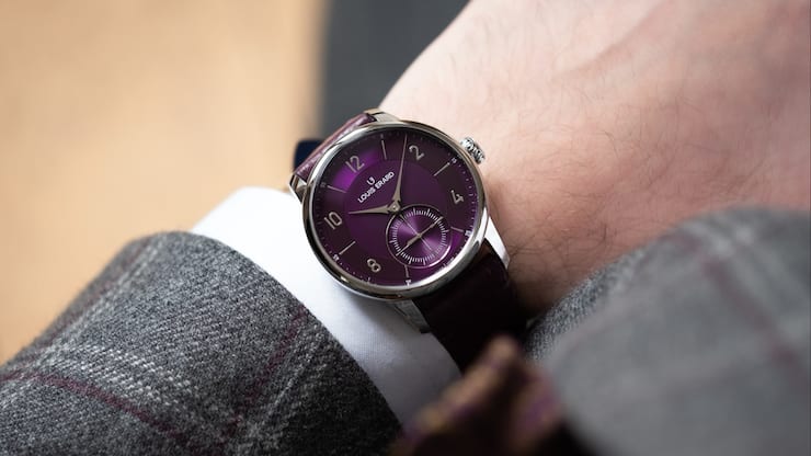 Violette Uhr von Louis Erard am Handgelenk eines Mannes.