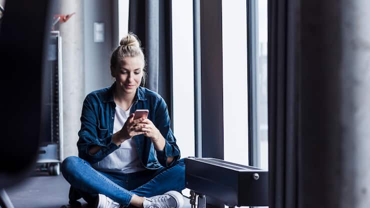 Woman sitting in an office using a smartphone by the window model released, Symbolfoto property released, UUF34207