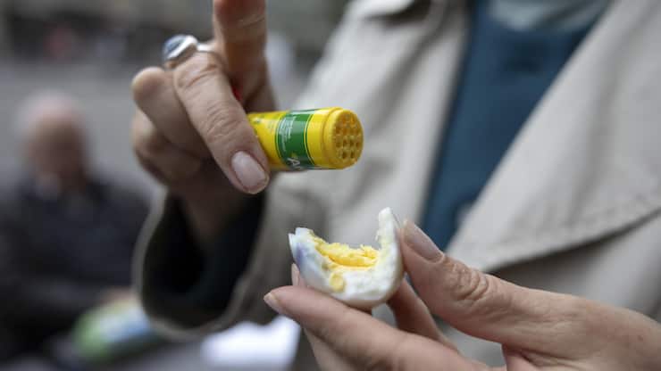 Eine Teilnehmerin streut Aromat ueber ihr Ei beim traditionellen Eiertuetschen am Ostersonntag, 31. Maerz 2024 in Bern. (KEYSTONE/Peter Klaunzer)