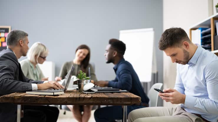 Distracted Businessman Using Mobile Phone In Meeting