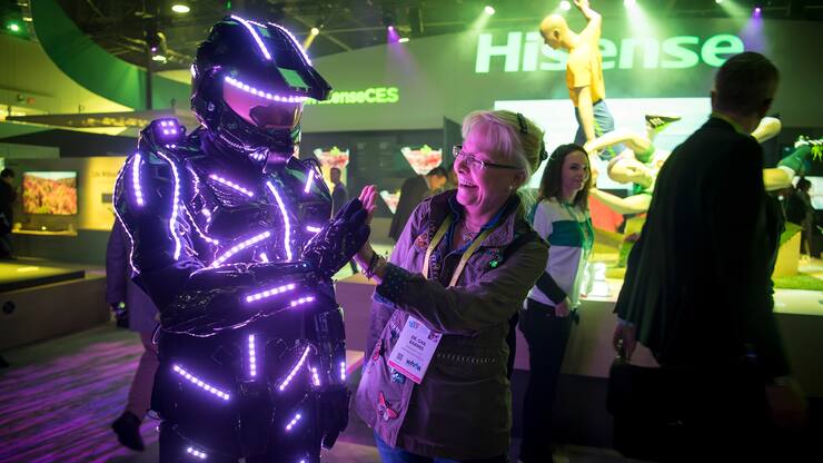 An attendee gives a high-five to a exhibitor wearing a suit with light-emitting diodes (LED) during the 2018 Consumer Electronics Show (CES) in Las Vegas, Nevada, U.S., on Thursday, Jan. 11, 2018.ÊElectric and driverless cars will remain a big part of this year's CES, as makers of high-tech cameras, batteries, and AI software vie to climb into automakers' dashboards. Photographer: David Paul Morris/Bloomberg via Getty Images