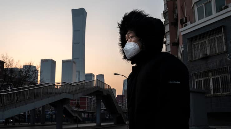 Mann in Beijing, China, vor der Skyline und trägt Maske.