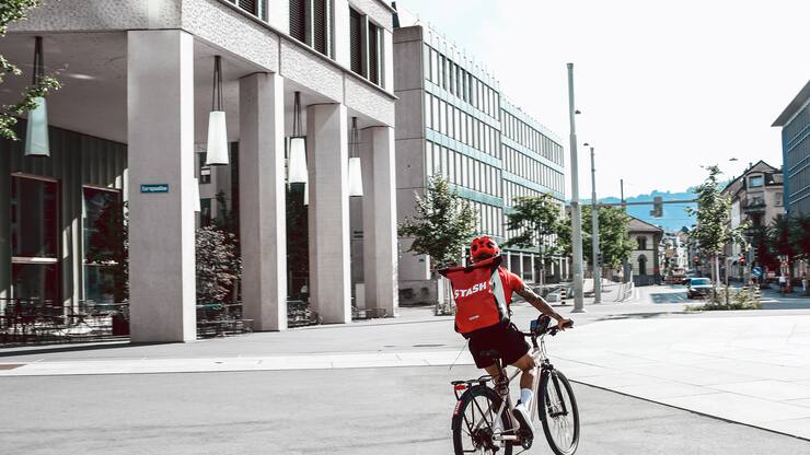 Ein Velokurier des Blitzlieferdienstes Stash mit rotem Rucksack.