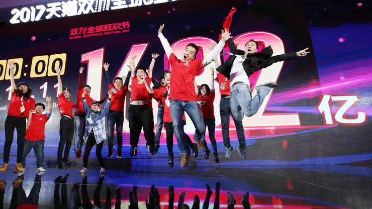 SHANGHAI, CHINA - NOVEMBER 12:  Staff members and journalists pose with the screen showing Alibaba's GMV of the Single's Day Global Shopping Festival at Shanghai Expo Centre on November 12, 2017 in Shanghai, China. Alibaba Group generated RMB 168.2 billion (or USD 25.3 billion) of gross merchandise volume (GMV) in the Single's Day Global Shopping Festival on Nov 11.  (Photo by VCG/VCG via Getty Images)