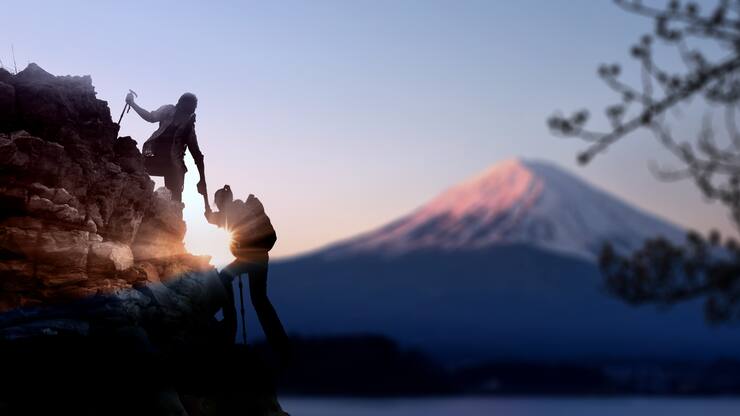 Young Asian couple  hikers climbing up on the peak of mountain near mountain Fuji .Climbing ,Helps and Team work concept .