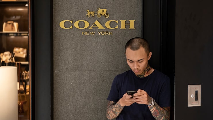 HONG KONG - 2019/04/08: A commuter seen using his smartphone outside of American multinational fashion and luxury accessories chain brand Coach store in Mong Kok shopping mall. (Photo by Budrul Chukrut/SOPA Images/LightRocket via Getty Images)