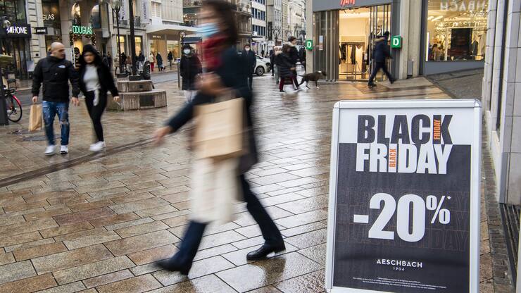Une personne passe devant une affiche qui indique des reductions, lors de la journee Black Friday dans un magasin a Geneve, ce vendredi 26 novembre 2021. (KEYSTONE/Martial Trezzini)