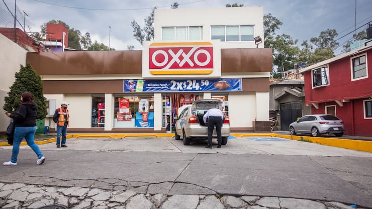 Mann packt Einkäufe ins Auto vor Oxxo-Laden