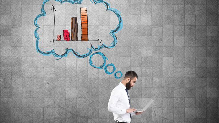 Side profile of a young businessman working on laptop and analyzing business graph on laptop which representing the business progress.