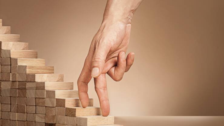 Eine Hand fährt über eine kleine Holztreppe