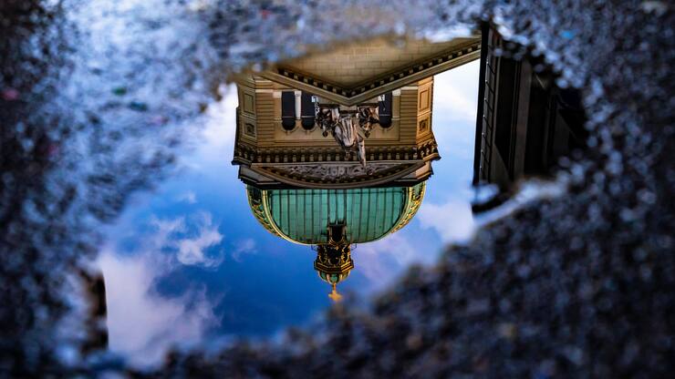 Das Bundeshaus in Bern spiegelt sich nach dem Regen in einer Pfütze.