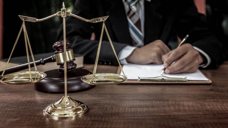 Tribunal attorney lawyer working with documents and wooden judge gavel on table in courtroom.