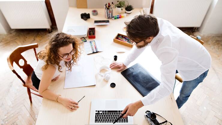 Two young architects with laptop consulting a project together. Designers and team workers in creative office.