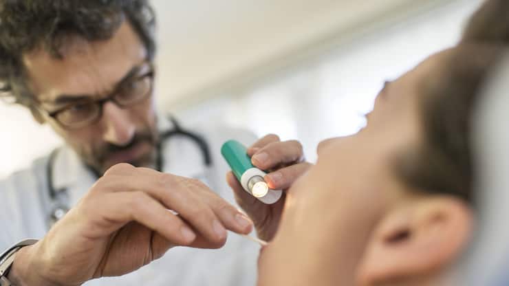 [EDITORS NOTE: POSED PICTURE] A doctor examinates throut and mouth of a patient, pictured on March 28, 2014. (KEYSTONE/Christian Beutler)