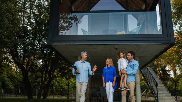 Family standing outside of their new home with their real estate agent