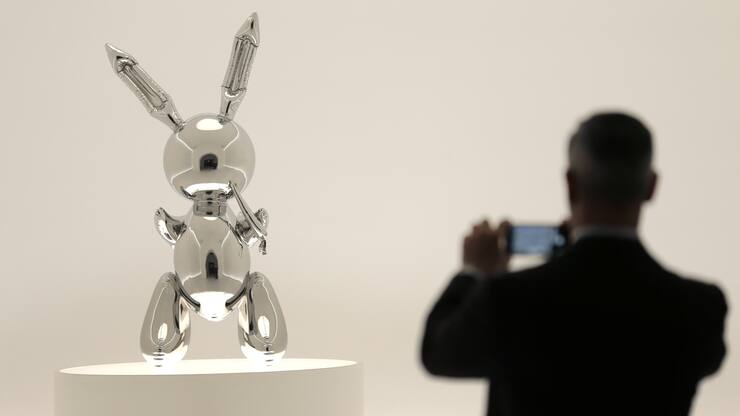 A man takes a picture of a sculpture entitled "Rabbit" by Jeff Koons during a media preview at Christie's in New York, Friday, May 3, 2019. This sculpture along with other artworks will be sold in series of auctions starting on May 13, 2019. (AP Photo/Seth Wenig)