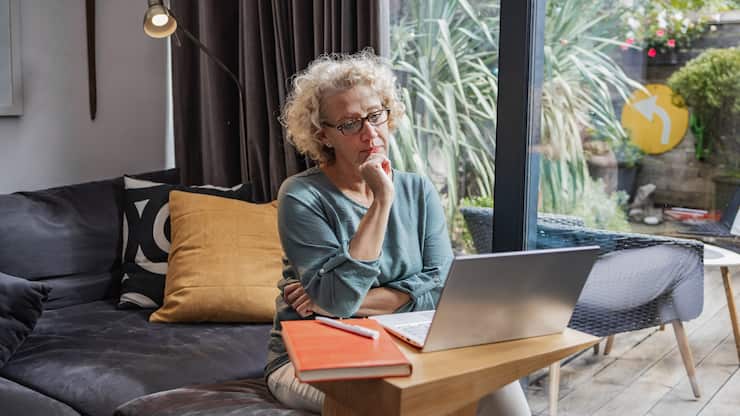 Mature woman with eyeglasses, remote working. Small business owner working from home in a modern apartment.