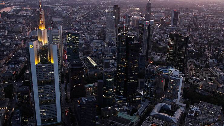 The headquarters of Commerzbank (L) and the twin towers of Deutsche Bank (R) stand illuminated amid the skyline 