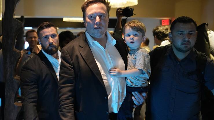 Twitter CEO Elon Musk, center, carries his child as he leaves after speaking at the POSSIBLE marketing conference, Tuesday, April 18, 2023, in Miami Beach, Fla. (AP Photo/Rebecca Blackwell)